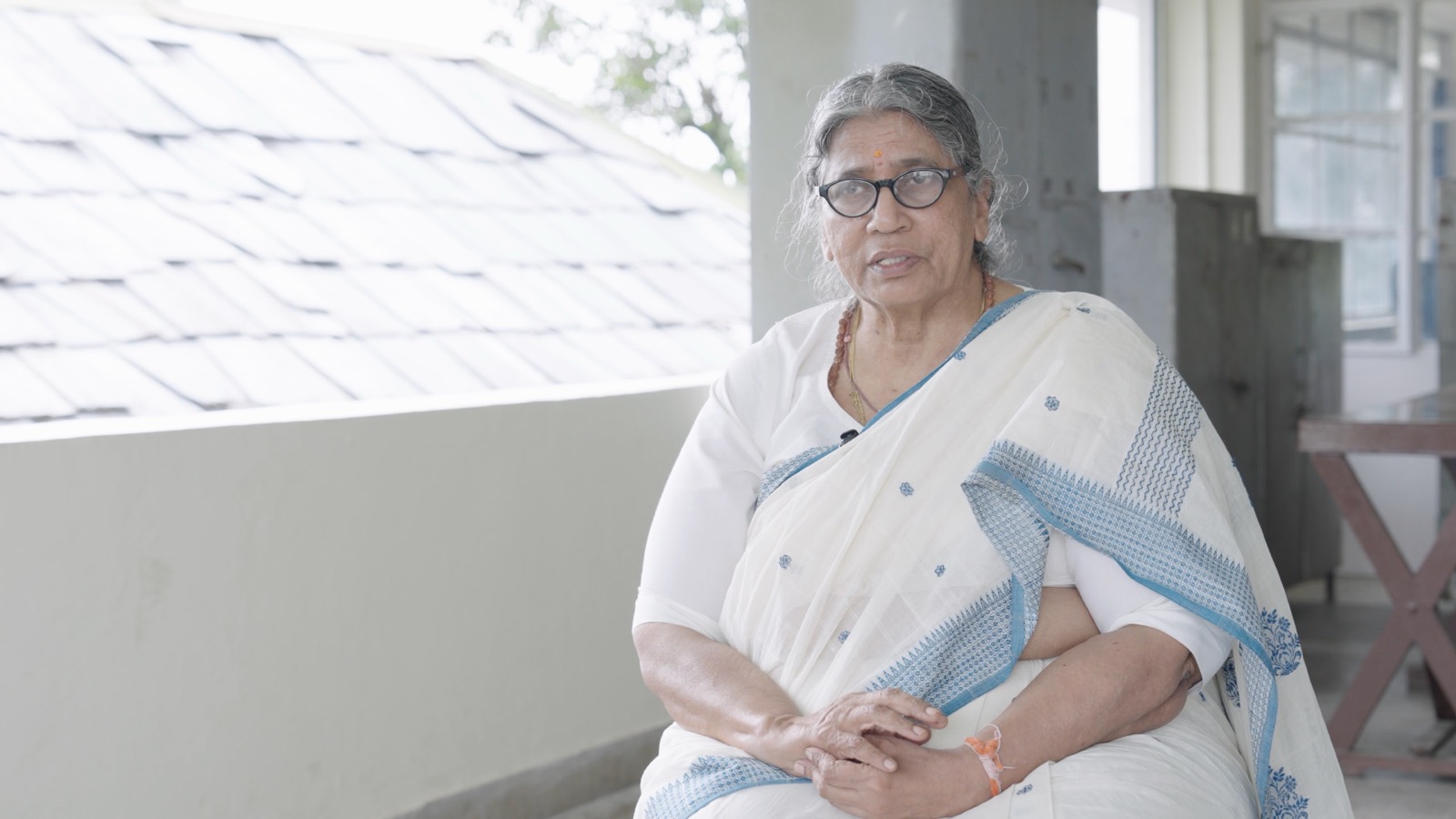 A woman in a white sari speaking on a veranda at the CORD campus