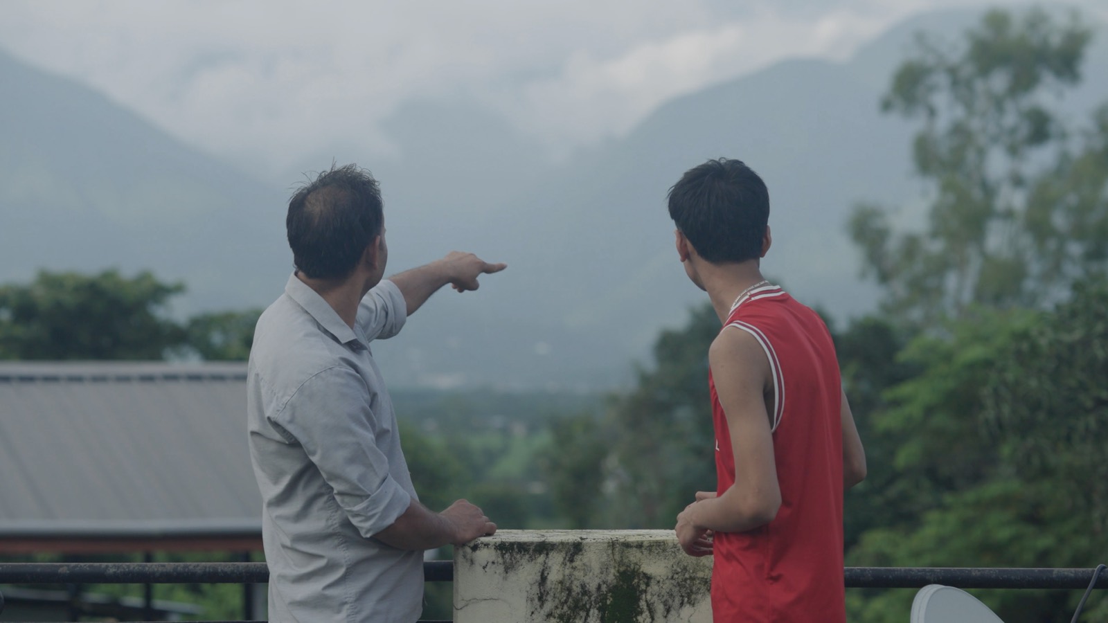 A teacher points out across the valley to a young student standing beside him